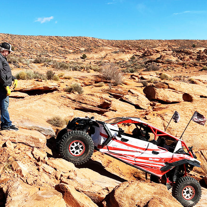 DIRT WARRIOR ACCESSORIES UTV / SXS windshields, vault enclosures, windshield wipers, accessories - DWA  UTV / SXS Off-road vehicle on rocky terrain with a person observing